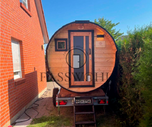 Eine Fasswohl Fasssauna in der Einfahrt eines Kunden zwischen Haus und Hecke