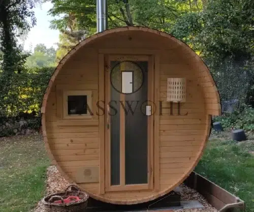 Eine Holzfasssauna im Garten mit Utensilien im Vordergrund