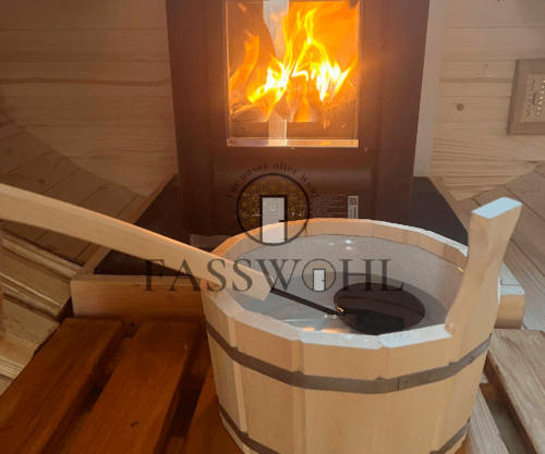 Im Vordergrund befindet sich der Eimer mit dem Aufguss und im Hintergrund ein brennender Ofen