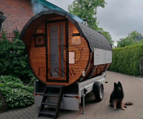 Ein Hund der neben dem Saunafass sitzt