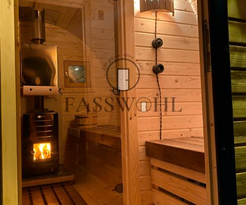 Eine Fasssauna von innen, in der Spiegelung der Scheibe sieht man das Fasswohl Logo