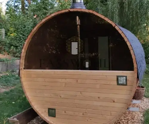 Eine Fasssauna im Garten von hinten fotografiert