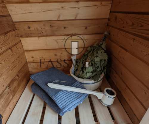 Handtuch, Aufgusseimer und Kräuter in der Fasssauna