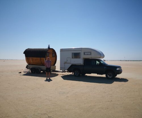 Eine Fasswohl Fasssauna wird auf einem Anhänger von einem Auto gezogen