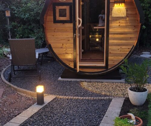 Eine Fasssauna auf einem schönen Steinweg von einem Fasswohl Kunden